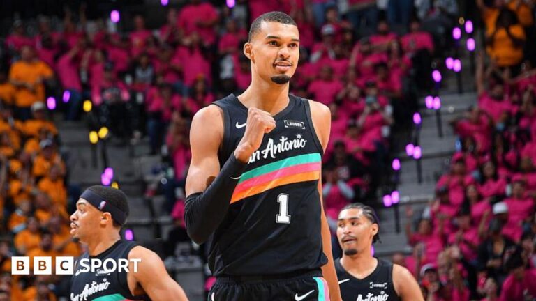 NBA: Victor Wembanyama stars for Spurs as Thunder and Celtics win Victor Wembanyama, wearing a black San Antonio vest with a turquoise, pink, and orange stripe across the chest, punches his right fist in celebration and smiles