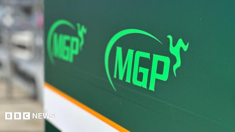 Rider dies after Manx Grand Prix qualifying crash A large green sign with the MGP logo on it in pitlane.
