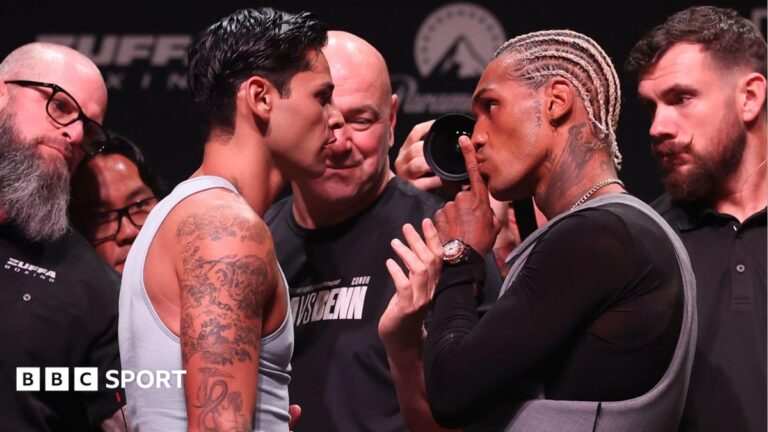 Ryan Garcia has his hand in his pocket as he looks at Conor Benn who is holding up his fist. The WBC welterweight title is being held between them